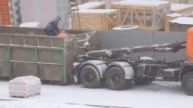 Загрузка КамАЗа пухтовоза Автокраном, зимой в снегопад на стройке.