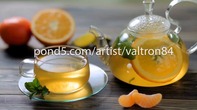 Glass teapot and Cup with green tea, orange, Mandarin, lime and mint on brown wooden table