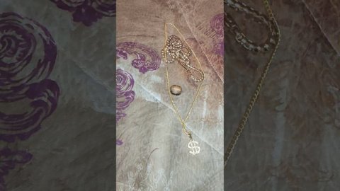 золотая цепочка ,кольцо и бусы с украшением доллар со стороны драгоценных камней, лежат вместе