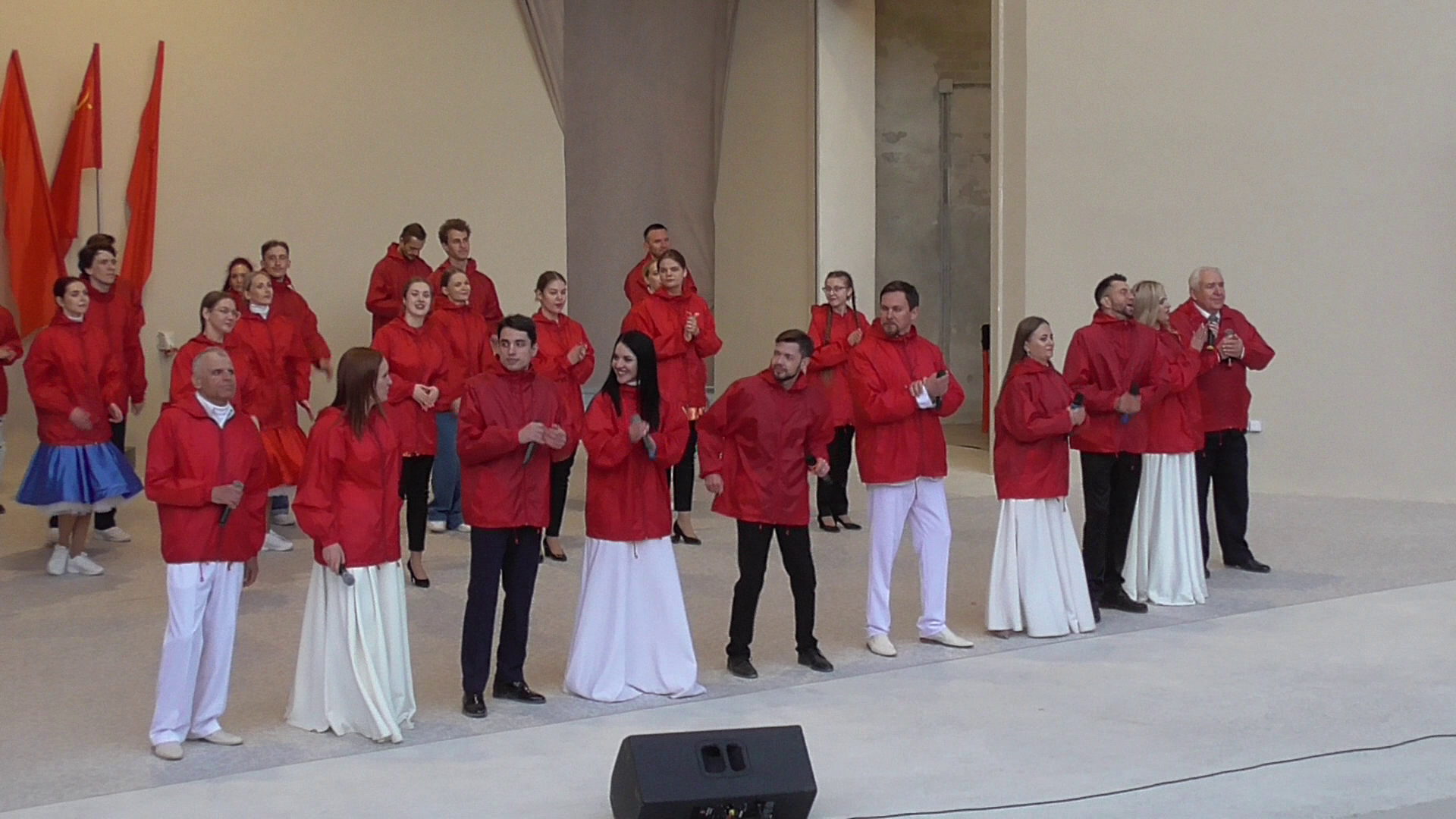Артисты в красных куртках поют песню