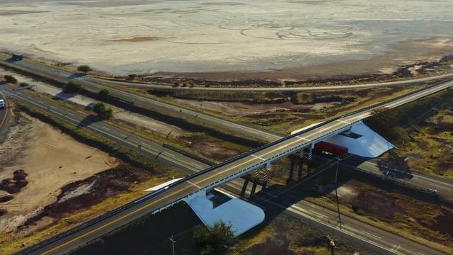 Mixkit-flying-over-a-highway-overpass-with-a-dry-lake-and-52007-hd-ready