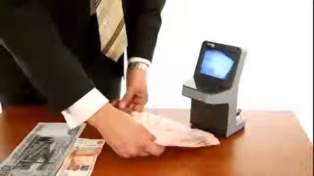 мужчина внимательно проверяет купюры на детекторе валют