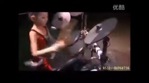 маленькая китайская девочка играет на электронных барабанах.