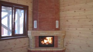 Угловой камин с чугунной топкой и отделкой из облицовочного и шамотного кирпича.