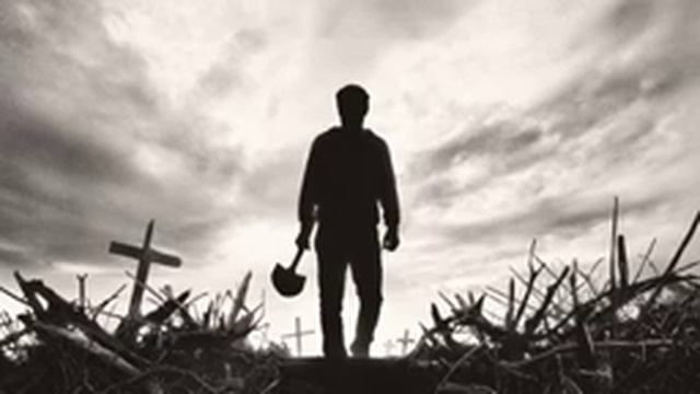 мужчина с лопатой на фоне кладбища