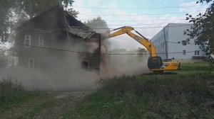 Большой экскаватор ломает старый дом