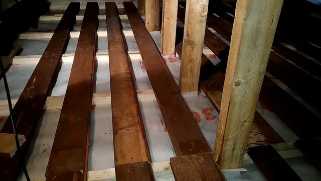 человек рассматривает балки перекрытия на чердаке