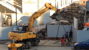 Экскаватор отрывает забор или снимает воротную дверь с петель