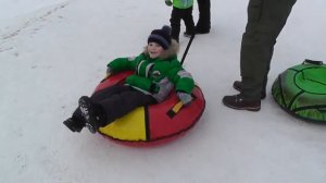 На ватрушке с очень высокой горки / дети и взрослые весело катаются на тюбинге