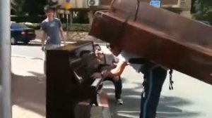 Грузчик играет с пианино на спине
