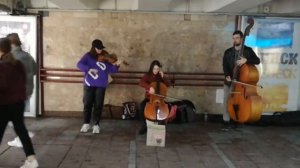Трио струнников играют популярные современные песни в переходе: скрипка, виолончель, контрабас - ч.