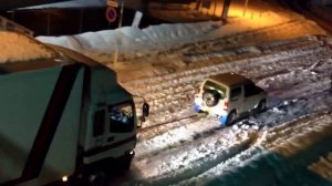Маленький автомобиль вытаскивает фуру из снега