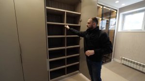 Современный шкаф для одежды в спальне с фасадами из бежевого мдф и бронзового стекла в черных рамках