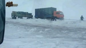 Вытягивает Грузовик КамАЗ с прицепом из снежного оврага.