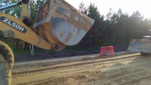 Грейдер и бульдозер выравнивают песок.