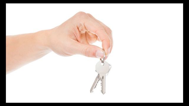 рука с ключами от квартиры на фоне судебной повестки