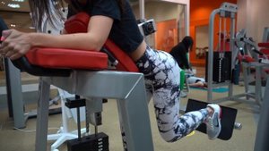 Тренажерный зал. Упражнения на ягодичные мышцы. Отведение одной ноги в тренажере кикбэк