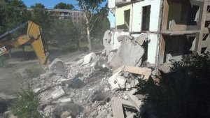 Снос пятиэтажного здания экскаватором.