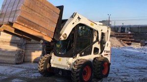 Разгрузка погрузчиком Bobcat S650 паллет с кирпичом весом 1300 кг с прицепа