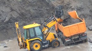 Экскаватор погрузчик загружает Камаз под дождём и поедет он видео.
