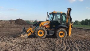 Экскаватор-погрузчик JCB 3CX Super на планировке участка под строительство
