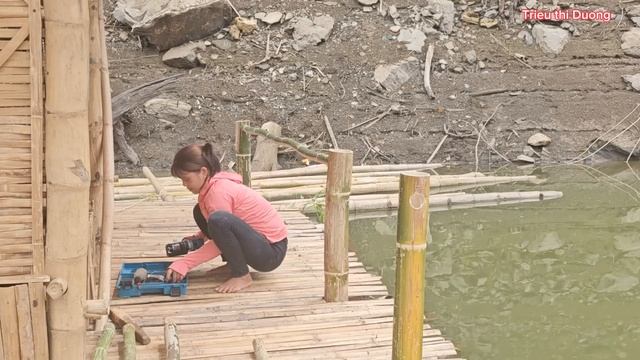 The girl designs the balustrade of the bamboo house floating on the water, catching fish to sell.