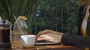 typing on her laptop in a coffee shop