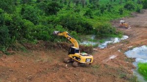 Строительство, экскаватор проводит зачистку участка от зарослей