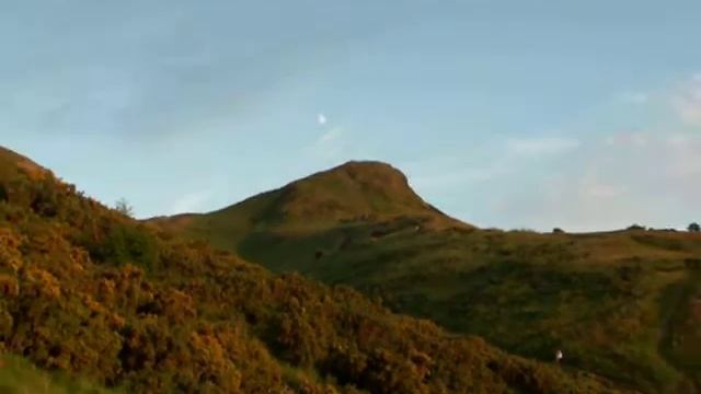 A gibbous moon hangs over the imposing mound of Arthurs Seat - Edinburgh