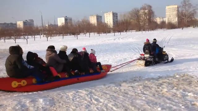 Катание Зимой детей на зимнем Банане за снегоходом