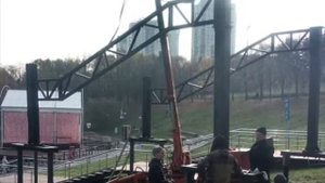 Мини кран паук в работе на лужайке в Олимпийской деревне