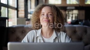 Girl Looks Out Window Smiles and Looks Into Camera While Sitting with Laptop in Cafe | Stock Foo...