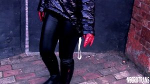 Spring walks of a girl in leather leggings, a black shiny jacket with a hood and a black gas mask