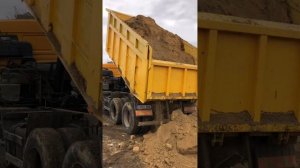 Kamaz 6540 Russian dump truck unloads clay in the mud