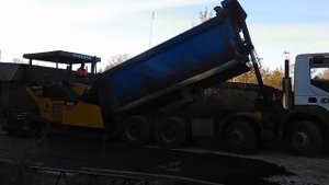 Загрузка асфальта в асфальтоукладчик грузовик самосвал