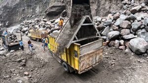 Строительство, экскаватор выкапывает песок из под большого камня