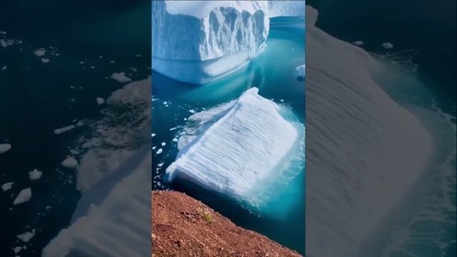 Айсберг переворачивается в водах крупнейшего в мире фьорда, Скорсби-фьорда, в Гренландии.