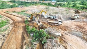 Экскаватор CAT 320 разбивает большие камни стальным шаром.