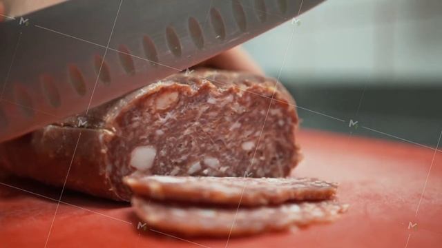 Cutting salami sausage on thin slices. Close up view of hand slicing meat sausage with a knife смотреть онлайн