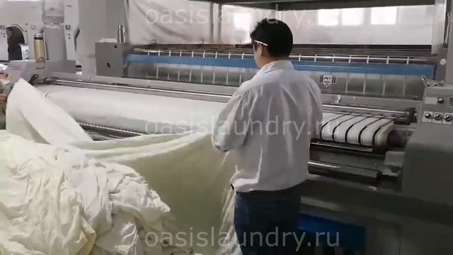 Подающая машина в работе. Профессиональное оборудование для прачечных