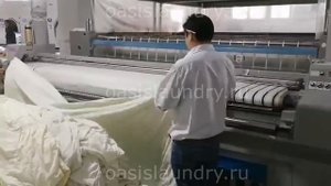 Подающая машина в работе. Профессиональное оборудование для прачечных