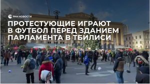 Протестующие играют в футбол перед зданием парламента в Тбилиси