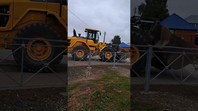 A loader with a bucket is driving along the road