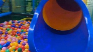 A child is playing on a playground and sliding down a slide with colorful balls
