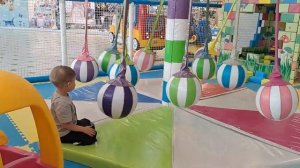 A child is sliding down a slide and jumping on a trampoline at a playground