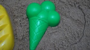 Playing with beach toys in the sandbox with sand molds with a pear and an apple