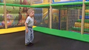 A child plays on a playground and slides down a slide with colored balls