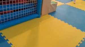 A child plays with balls on the playground and slides down a slide.