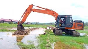 The Hitachi ZX210 excavator digs trenches in the middle of rice fields very quickly