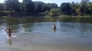 Папа и дочка играют с мячиком на речке.